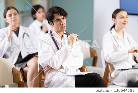Young female doctor listening and taking notes in lecture hall 136644585