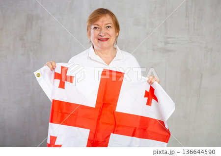 Smiling elderly woman waving national Georgian flag 136644590
