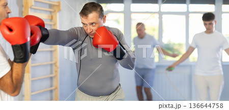 Men in boxing gloves punch deliver blow each other during training sparring session. Men in boxing gloves punch deliver blow each other during training sparring session. 136644758