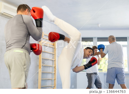 Man with young guy sparring during kickboxing training and practicing kicks Man with young guy sparring during kickboxing training and practicing kicks 136644763