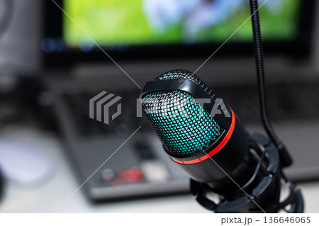 Detailed View of Recording Microphone Resting on Laptop Under Artistic Illumination 136646065