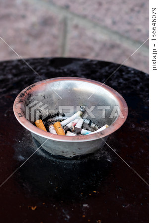 Rough urban landscape with smudged metallic container brimming with burning remnants and ember glow 136646079
