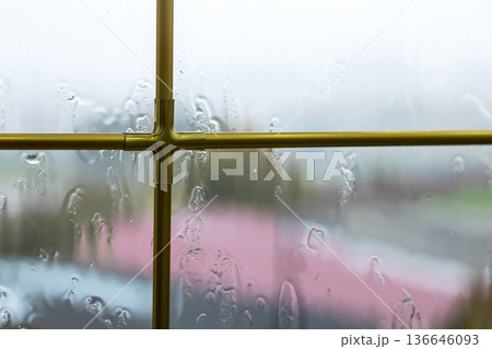 Rainy window scene. Gloomy window capturing blurred roof and subdued lighting atmosphere 136646093