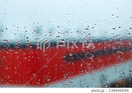 Raindrops on window with city view. City station scene with raindrops and soft lights reflected Raindrops on window with city view. City station scene with raindrops and soft lights reflected 136646094