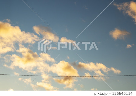Calm sunset with drifting clouds. Serene blue sky with illuminated clouds and open landscape Calm sunset with drifting clouds. Serene blue sky with illuminated clouds and open landscape 136646114