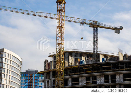 Highrise development with crane lifting precast elements amidst urban surroundings 136646363