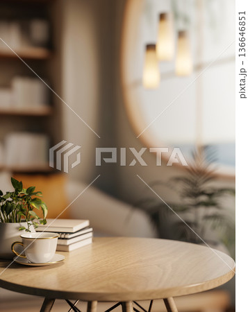 Coffee cup with book and pot plant on round wooden table and bookshelf aside window in a living room 136646851