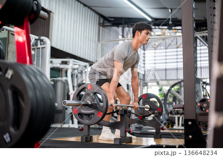 Asian man client in sportswear bending down holding barbell exercising doing weight lifting in gym. Asian man client in sportswear bending down holding barbell exercising doing weight lifting in gym. 136648234