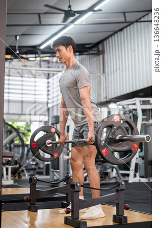 Strong asian man client in sportswear standing holding barbell exercising doing weight lift in gym. 136648236