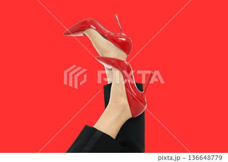 A woman shows off red high heels with legs raised A woman shows off red high heels with legs raised 136648779