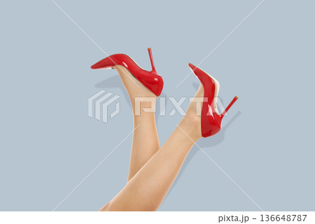 Bright red high heel shoes are presented with legs crossed 136648787