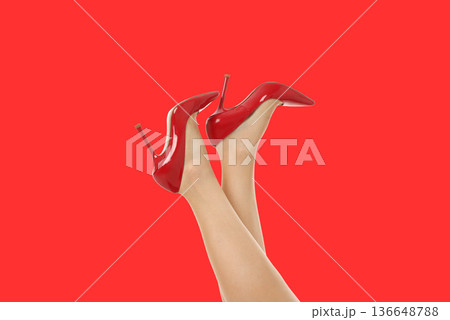 A young woman displays her legs and red high-heeled shoes 136648788