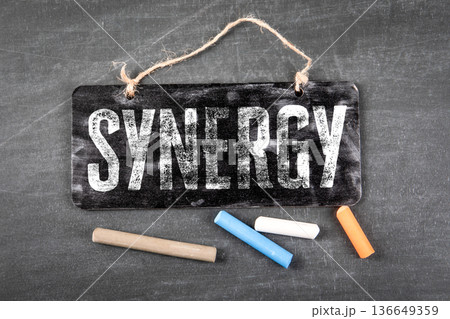 Synergy Business Concept With Hanging Blackboard Sign And Color Chalk On Desk 136649359