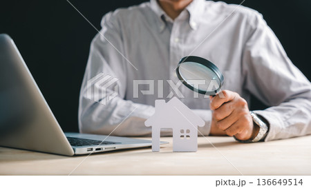 Real estate appraisal, inspector with magnifying glass on house model, searching property for home valuation, performing thorough inspection analysis using laptop technology 136649514
