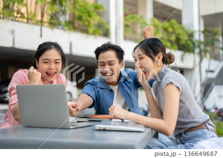 Happy asian man woman student friend looking at laptop in excited as sitting at table in university Happy asian man woman student friend looking at laptop in excited as sitting at table in university 136649687