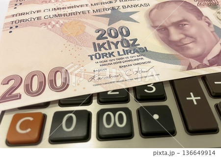 Turkish Lira and Calculator Finance Concept. 200 TRY banknotes on calculator representing Turkish economy, budgeting, and financial planning. 200 Turkish Lira banknotes placed on a black calculator. Turkish Lira and Calculator Finance Concept. 200 TRY banknotes on calculator representing Turkish economy, budgeting, and financial planning. 200 Turkish Lira banknotes placed on a black calculator. 136649914