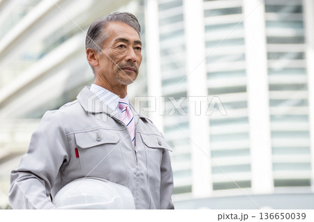 建設現場に立つ作業服のシニア男性 建設現場に立つ作業服のシニア男性 136650039