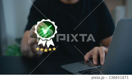 Person Holding a Green Check Mark Badge Symbolizing Achievement with Laptop on Table in Modern Office Setting Person Holding a Green Check Mark Badge Symbolizing Achievement with Laptop on Table in Modern Office Setting 136651871