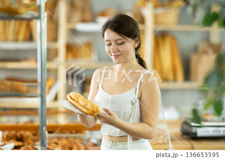 Portrait of a young girl with a bocadillo in her hands in the interior of private bakery 136653595