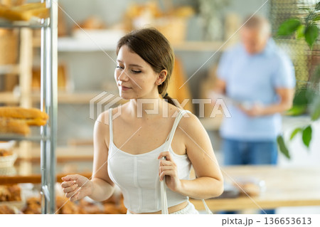 Girl choosing fresh baked goods on display in private bakery 136653613