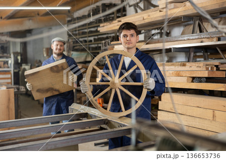 Young guy carpenter with wooden wheel Young guy carpenter with wooden wheel 136653736