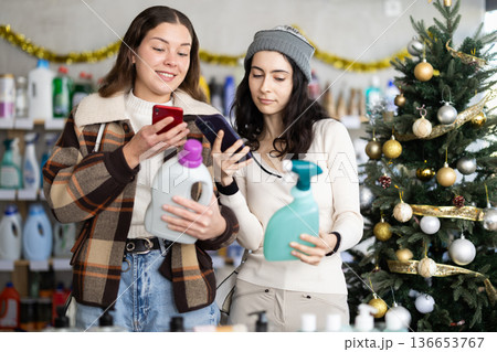 Female friends client scanning QR code on package laundry fabric softener and tile cleaner Female friends client scanning QR code on package laundry fabric softener and tile cleaner 136653767