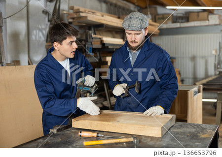 Young men fixing wooden board with clamp 136653796
