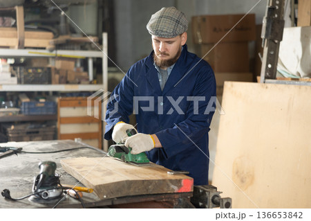 Man using a jigsaw machine on wooden plank at workshop Man using a jigsaw machine on wooden plank at workshop 136653842