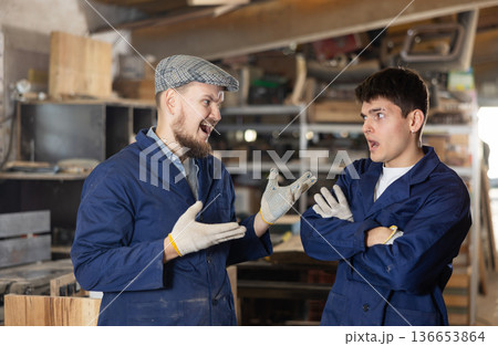 Young male carpenters quarreling in workshop Young male carpenters quarreling in workshop 136653864