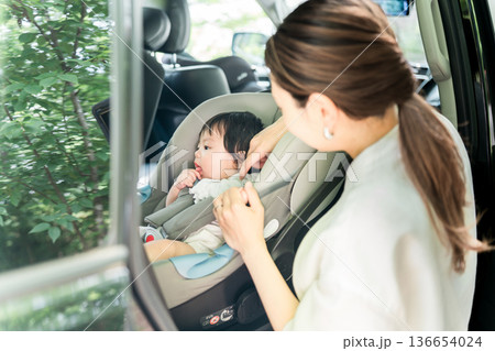 自動車のチャイルドシートに赤ちゃんを座らせる母親 136654024
