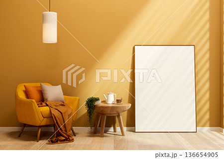 Yellow sofa chair under hanging lamp and coffee on side table with white frame leaning against wall. 136654905