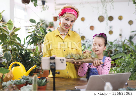 A woman and a young girl are holding air plants in a wooden planter, possibly for a video A woman and a young girl are holding air plants in a wooden planter, possibly for a video 136655062