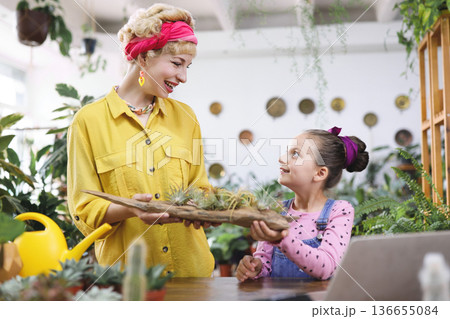 A woman and a young girl share a moment while admiring a display of air plants A woman and a young girl share a moment while admiring a display of air plants 136655084