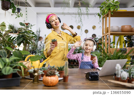 A mother and daughter enjoy their plants while listening to music together, creating a joyful moment A mother and daughter enjoy their plants while listening to music together, creating a joyful moment 136655090