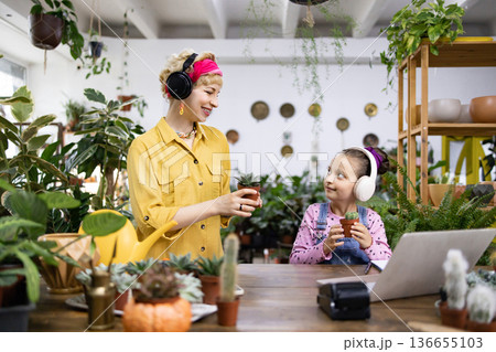 A woman and a girl are enjoying plants and music in a bright, inviting space A woman and a girl are enjoying plants and music in a bright, inviting space 136655103