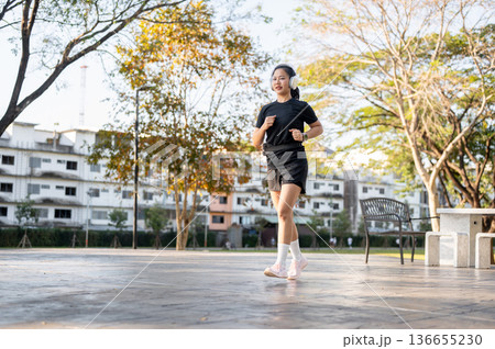 Asian woman in sportswear listening to music in headphone while running or jogging exercise in park Asian woman in sportswear listening to music in headphone while running or jogging exercise in park 136655230