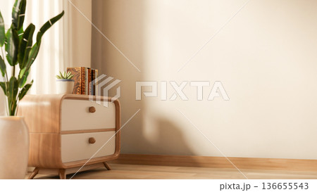 Book and potted plant on wooden drawer table and vase on parquet floor with sunlight through curtain 136655543