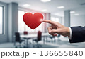 Businessman Pointing at Floating Red Heart Icon in Modern Office 136655840