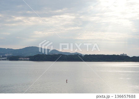 雲間から光が差し込む静かな湖畔の風景 136657688