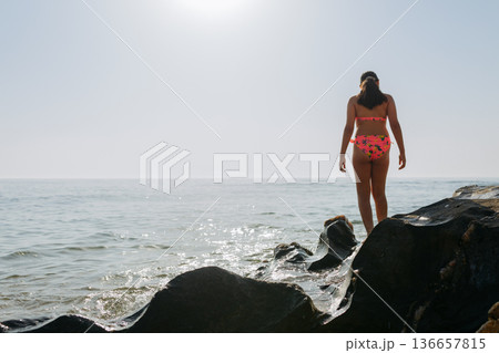 close-up view of a child legs standing on the rocks next to the sea close-up view of a child legs standing on the rocks next to the sea 136657815
