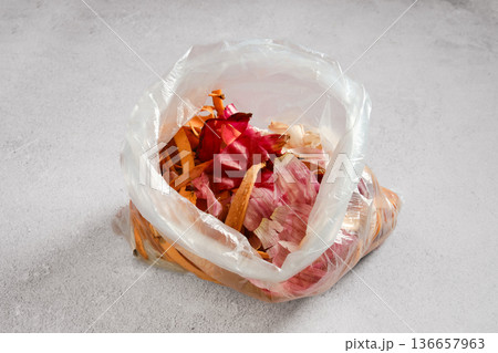 Waste bag filled with vegetable scraps and peels on a kitchen surface during meal prep Waste bag filled with vegetable scraps and peels on a kitchen surface during meal prep 136657963