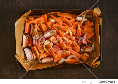 Seasoned sweet potatoes, garlic and onion on tray for healthy home roasting 136657964