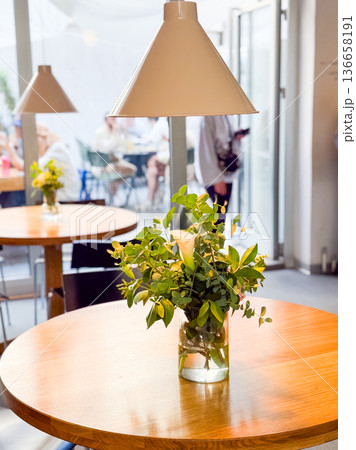 Flower bouquet with white calla in glass vase on cafe table. Decoration, lifestyle, and social gathering culture. Flower bouquet with white calla in glass vase on cafe table. Decoration, lifestyle, and social gathering culture. 136658191