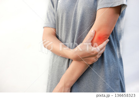 Young woman suffering from acute elbow pain and joint inflammation with red highlight effect, female touching sore arm, tendonitis, sports injury, arthritis, health problem, copy space background. Young woman suffering from acute elbow pain and joint inflammation with red highlight effect, female touching sore arm, tendonitis, sports injury, arthritis, health problem, copy space background. 136658323