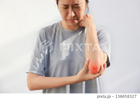 Young woman suffering from acute elbow pain and joint inflammation with red highlight effect, female touching sore arm, tendonitis, sports injury, arthritis, health problem, copy space background. Young woman suffering from acute elbow pain and joint inflammation with red highlight effect, female touching sore arm, tendonitis, sports injury, arthritis, health problem, copy space background. 136658327