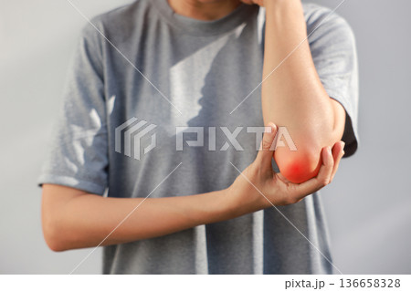 Young woman suffering from acute elbow pain and joint inflammation with red highlight effect, female touching sore arm, tendonitis, sports injury, arthritis, health problem, copy space background. Young woman suffering from acute elbow pain and joint inflammation with red highlight effect, female touching sore arm, tendonitis, sports injury, arthritis, health problem, copy space background. 136658328