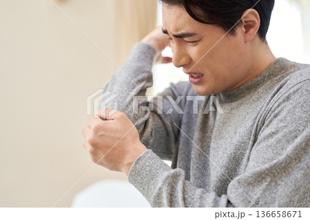 肘が痛くて手を当てるアジア人男性 136658671