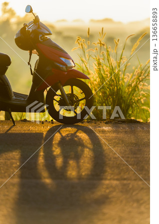 Silhouette of a red scooter in fog at sunrise, atmospheric minimalist landscape with a sense of silence, calm and solitude. High quality photo Silhouette of a red scooter in fog at sunrise, atmospheric minimalist landscape with a sense of silence, calm and solitude. High quality photo 136658893