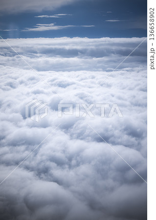 A view shows thick clouds spread across the sky. Blue areas peek through the clouds in the background. Daylight shines on this scene from above the earth. High quality photo 136658902