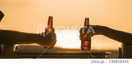 beer bottles in the hands of vacationers, which are held by a couple of lovers or friends. Camping together on the beach and a trip to a warm country for a honeymoon. High quality photo 136658938